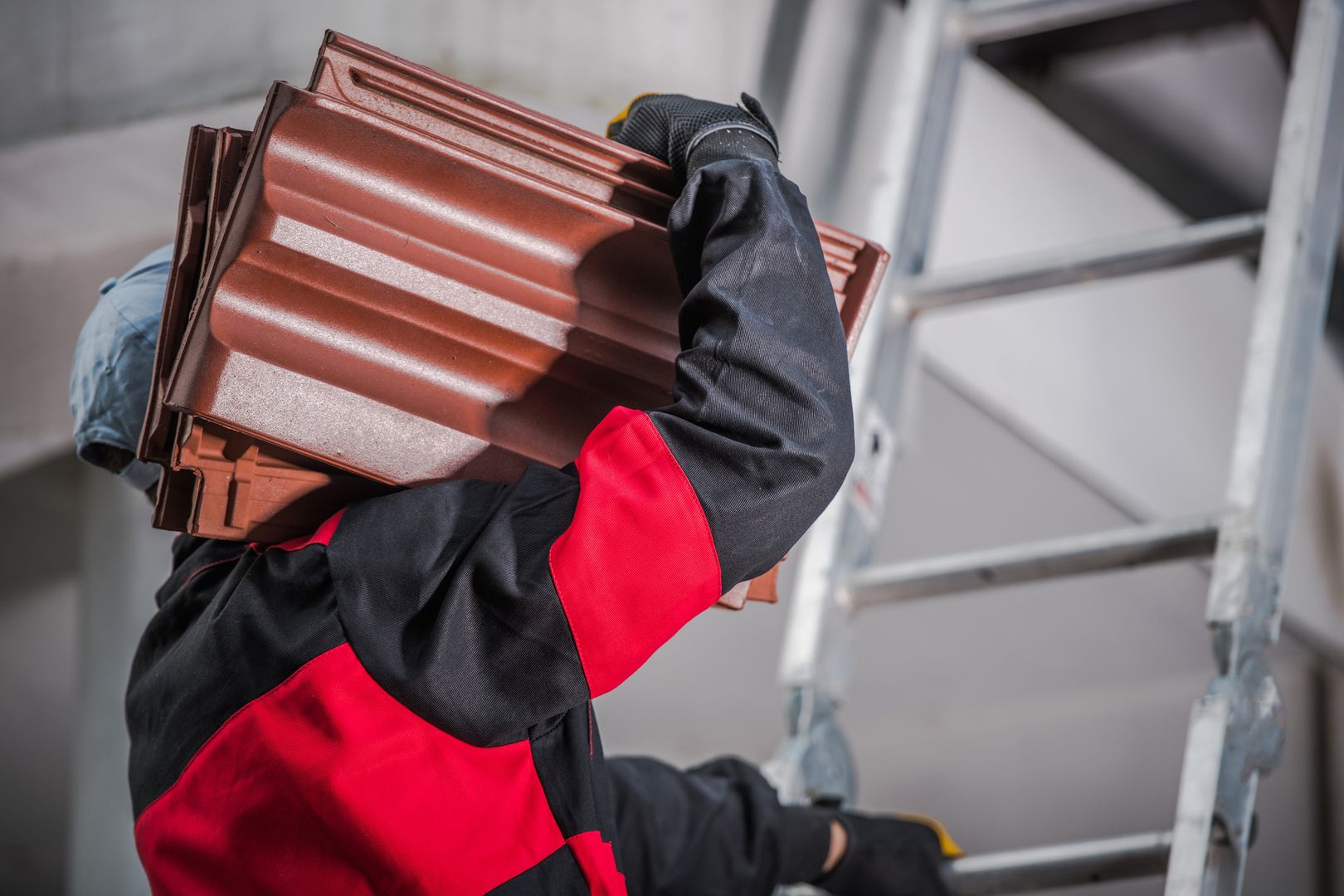 Ein Dachdecker trägt Schieferplatten